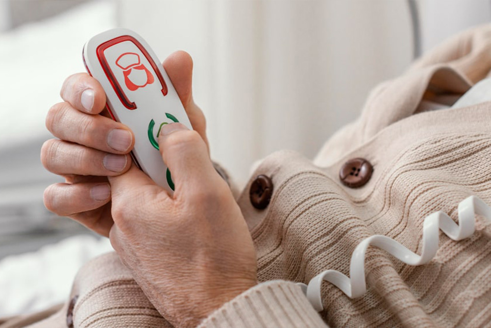 Senior hält Notrufsender in der Hand – Vital Experten bietet Hausnotrufsysteme für schnelle Hilfe im Notfall.